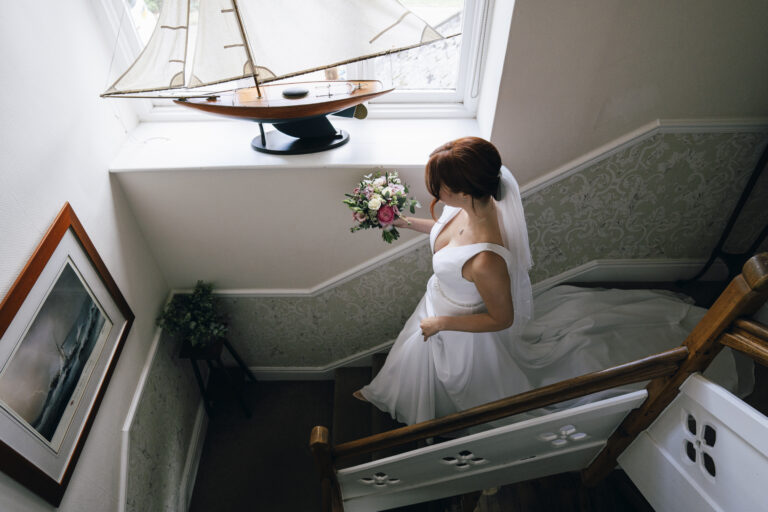 The bride walking downstairs in her wedding dress
